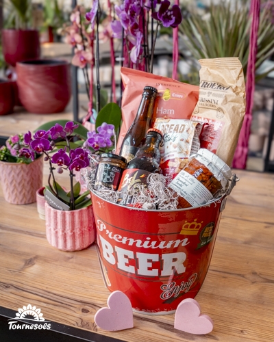 Panier garni Saint-Valentin avec bières artisanales, terrines et snacks gourmands du terroir, présenté dans un seau rouge.